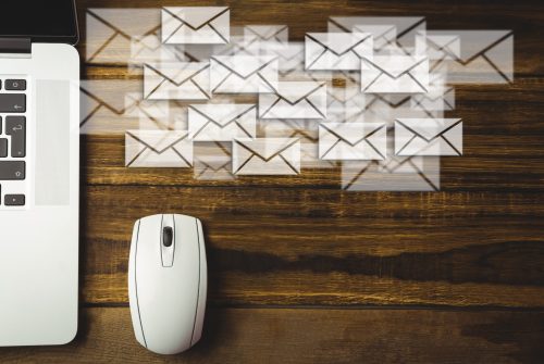 Composite image of laptop and mouse put on a desk with letter icons